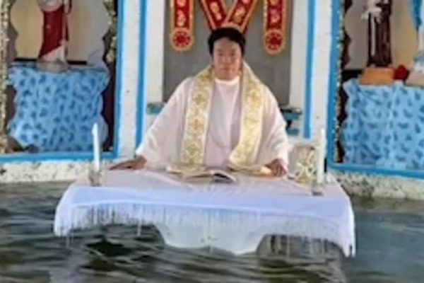 A priest continues to operate on a boat in the flooded church