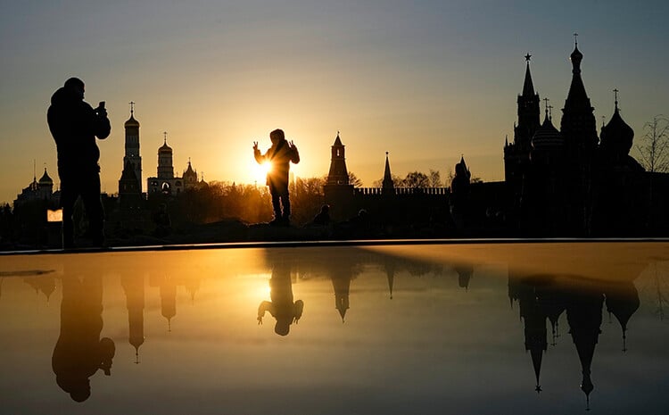 A woman is photographed against the backdrop of the Kremlin