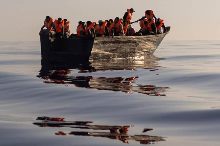 Мигранты в спасательных жилетах в лодке