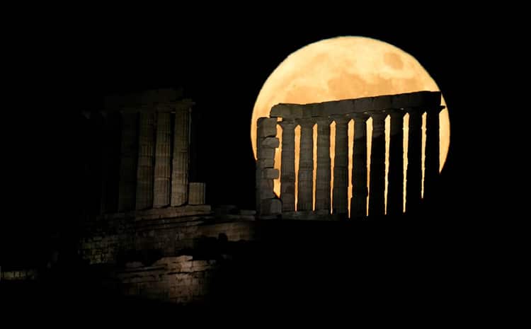 Sounio, Greece: The 'strawberry moon' emerges from behind the Temple of Poseidon